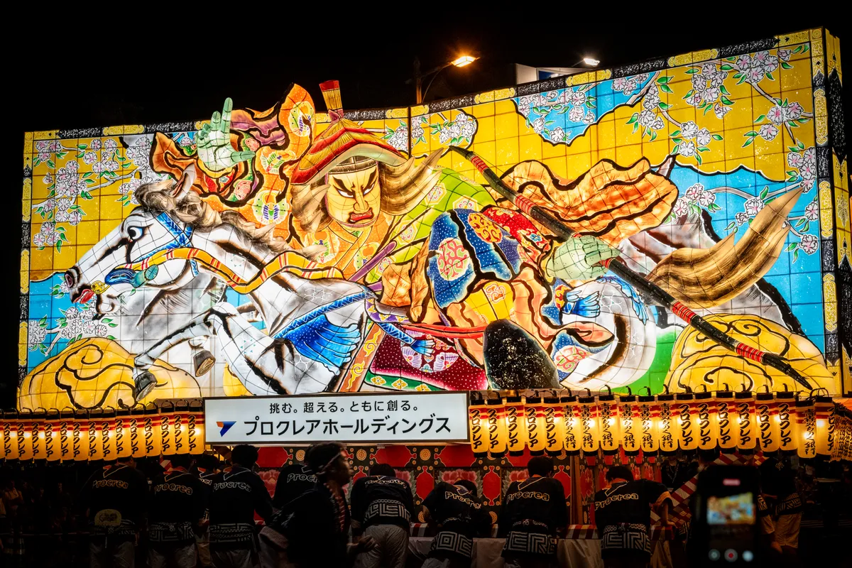 Festival participants push an illuminated Nebuta parade float depicting historical, mythological and kabuki characters through the streets of Aomori at night