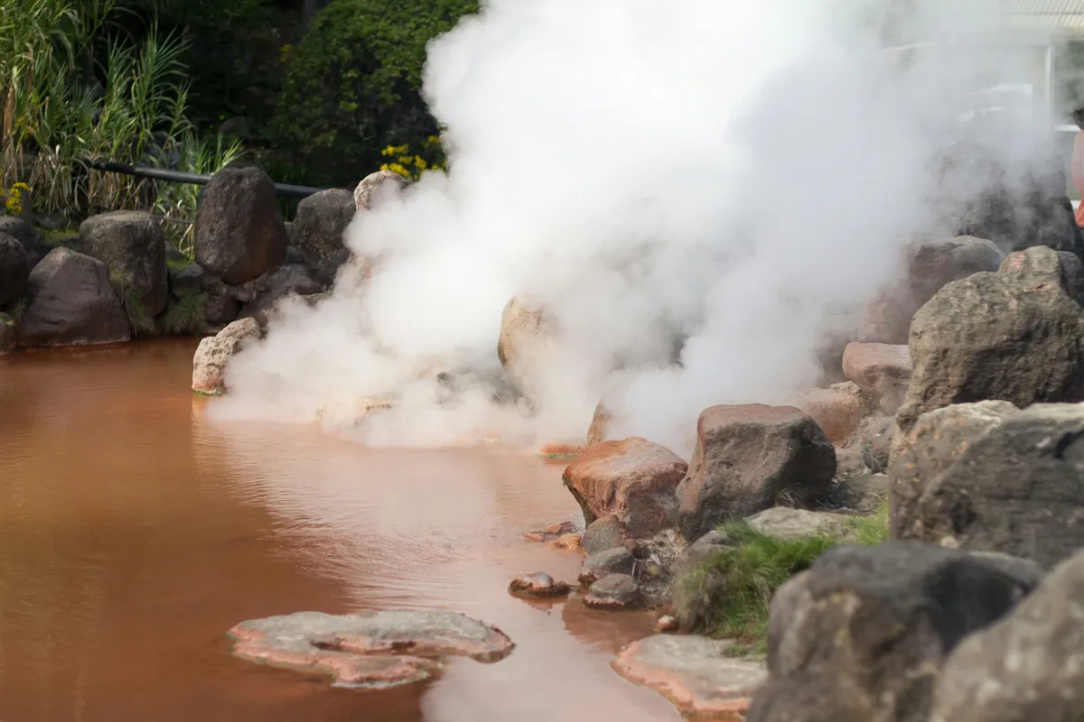 Steaming reddish-brown hot spring pool at one of Beppu's famous jigoku hells