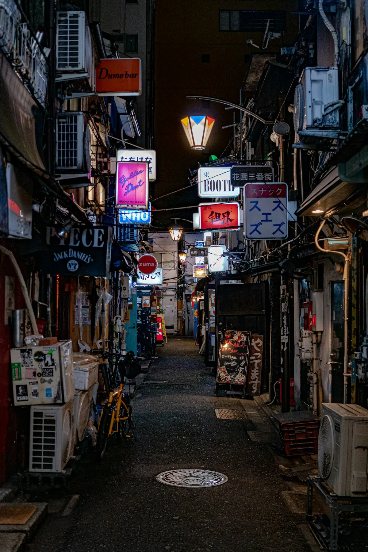 Narrow alley of Golden Gai in Shinjuku at night with glowing lanterns and bar signs