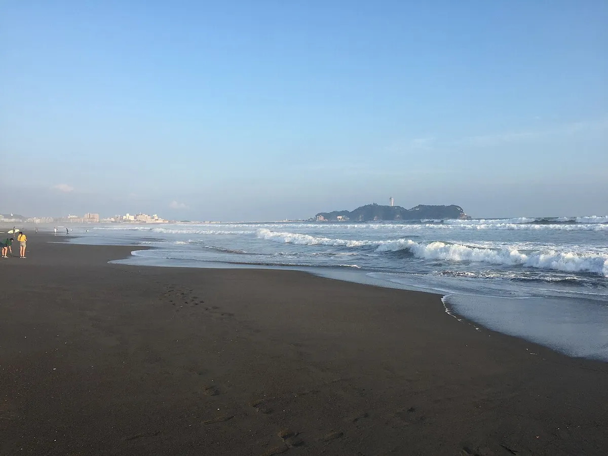 Enoshima Island seen across the shoreline and surf at Kugenuma Beach