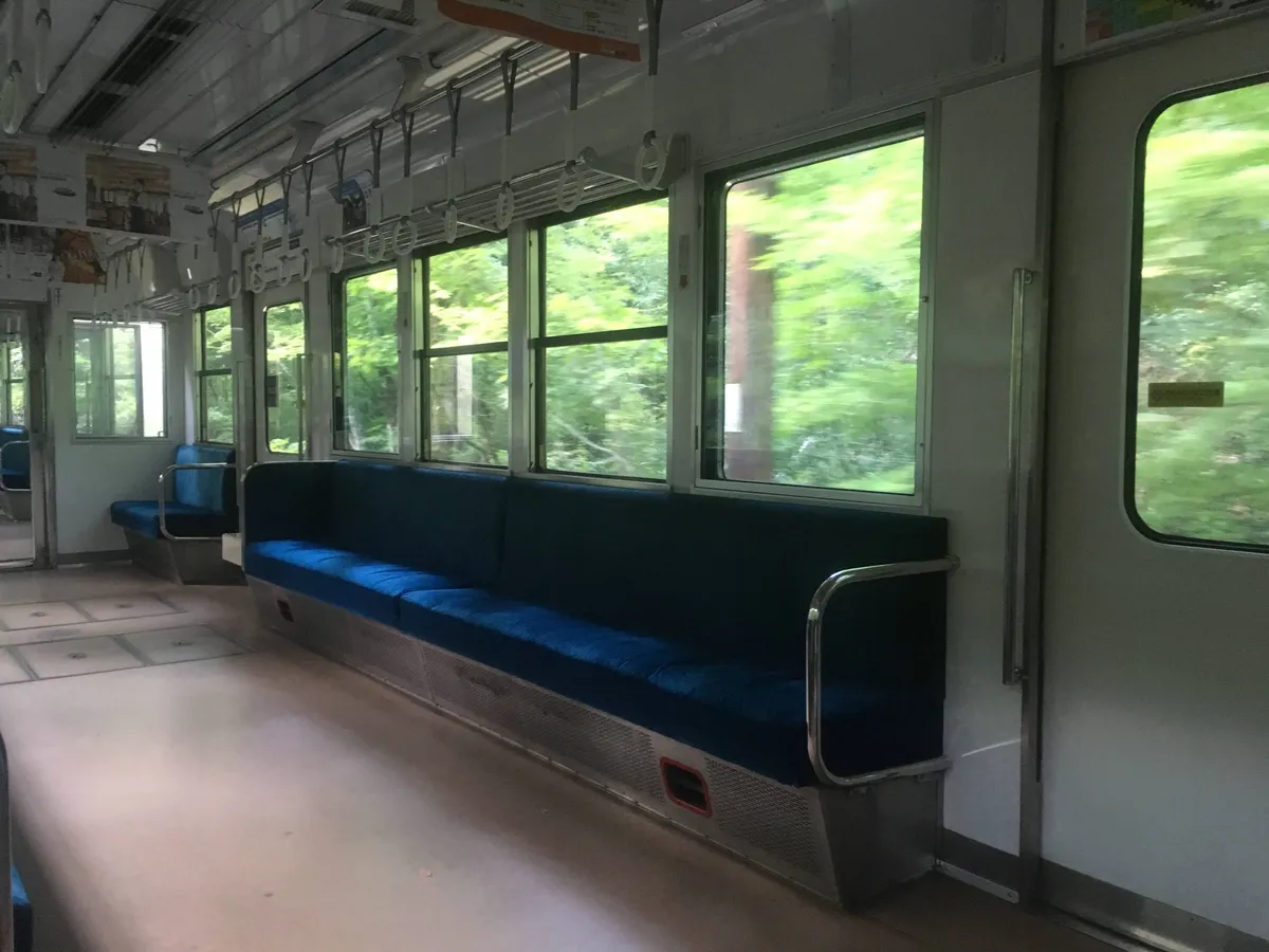 Inside the Eizan Railway train, passing through lush green forests on the way to Kibune