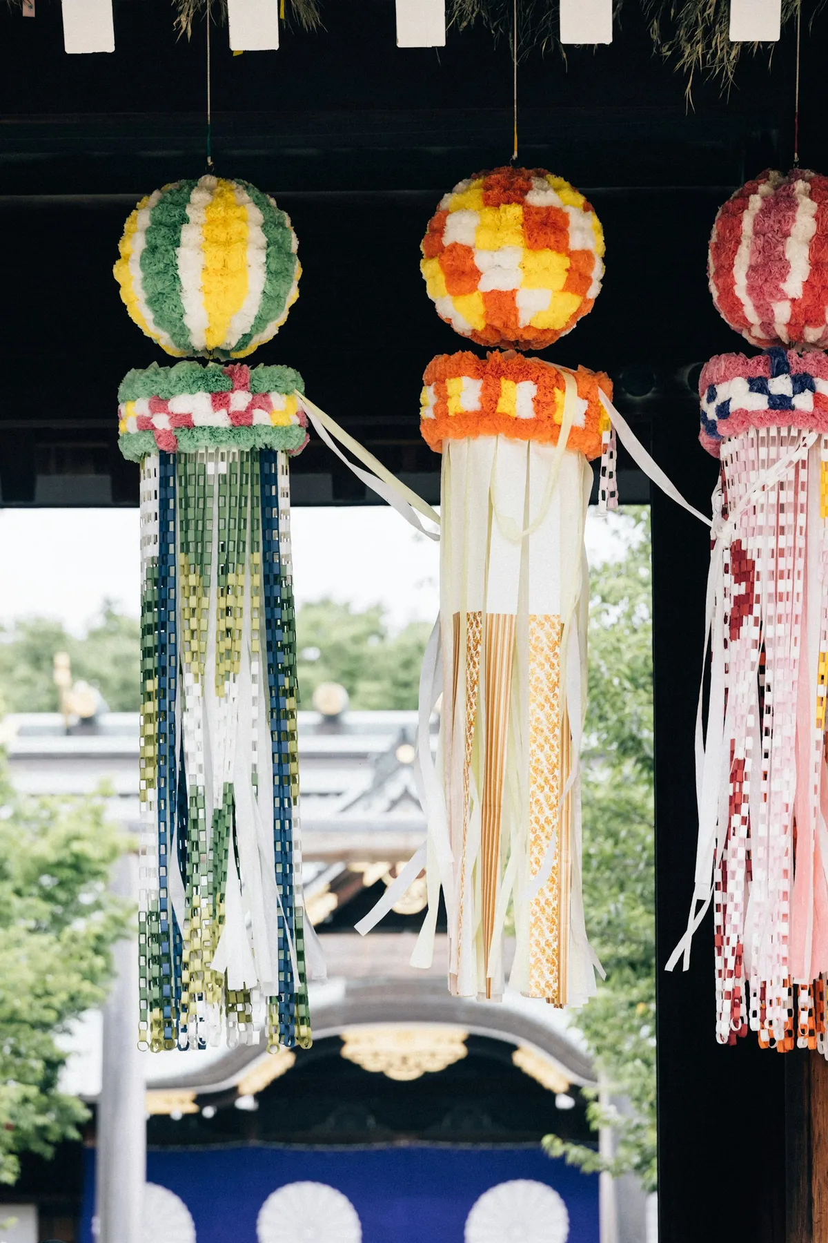 Colorful tanzaku paper wish strips and fukinagashi streamers hanging from a bamboo branch during a Tanabata festival in Japan